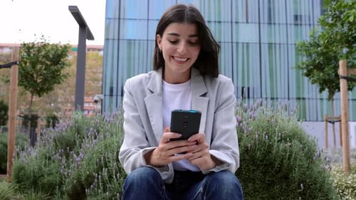 Successful Young Adult Businesswoman Using Smart Phone Over Business Building