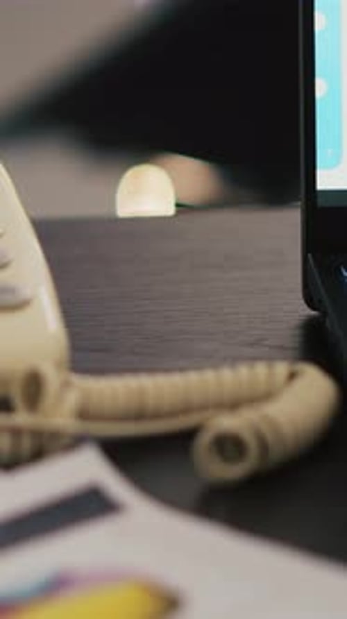 Vertical Video Report on Desk Next to Phone and Laptop Showing Stock Market Diagrams Close Up