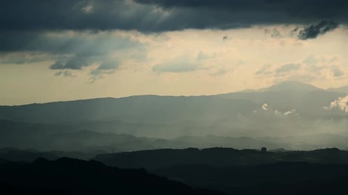 Above the cascading mountains, there are crepuscular light and dynamic clouds.