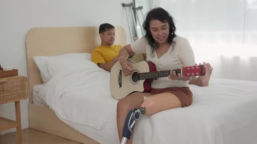 Woman Plays Guitar for Partner in Bedroom