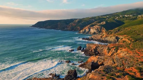 Turquoise ocean waves washing rugged volcanic coastline foaming in sunlight slow motion