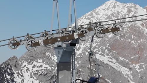 Cable Car Ski Mechanism with Gondolas Passing with Snowy Mountain Peak Background.