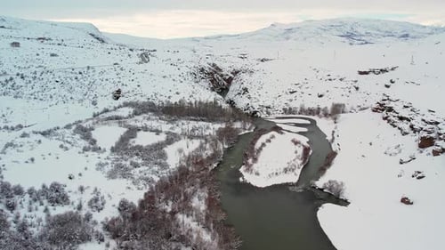 Aerial View of Snowy River Bend in Winter Mountain Landscape