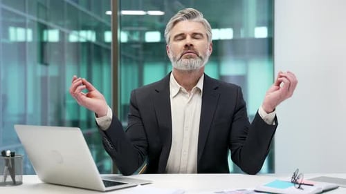 Man in Suit Meditates at Desk in Modern Office