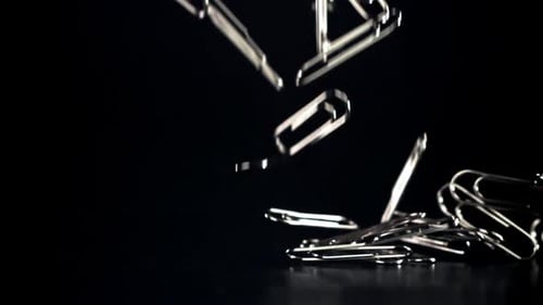Paperclips Falling on a Black Background in Slow Motion
