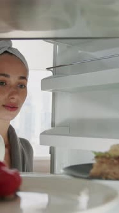 Woman gets cake from refrigerator inside home