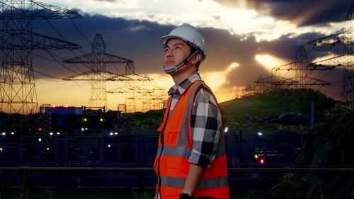 Side View Of Asian Male Engineer Looking Around Near High voltage tower