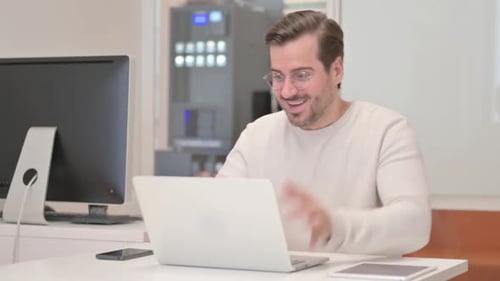 Excited Young Man Celebrating Success on Laptop in Office