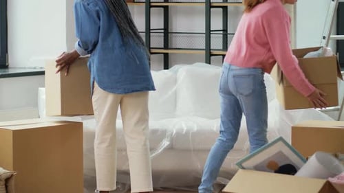 Moving, People And Real Estate Concept - Women With Boxes Resting On Sofa At New Home