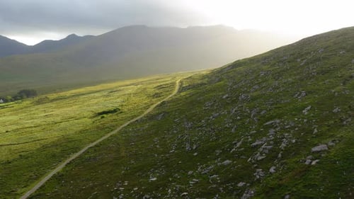 Aerial: Conor Pass during the day with green fields and fog in Brandon Point