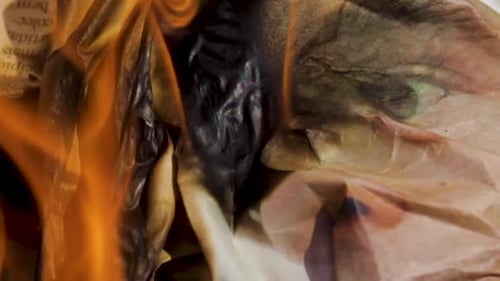 Several sheets of newspaper burning inside a metal container