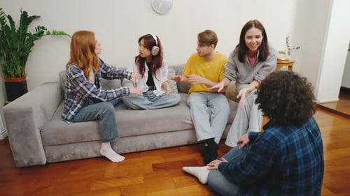 Groupe d'amis ayant une discussion animée dans un salon confortable lors d'une soirée décontractée