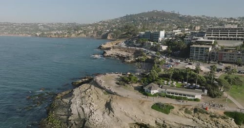 a beach with a large green field and buildings