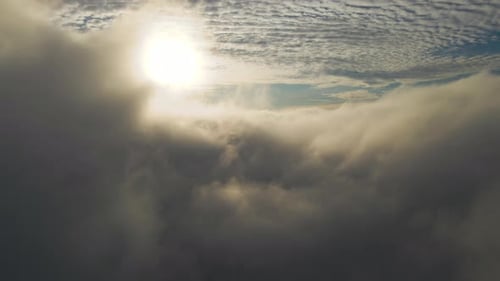 Aerial View of Vibrant Yellow Sunrise Over White Dense Clouds with Blue Sky Overhead