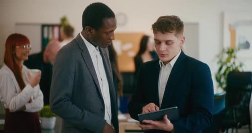 Colleagues Discussing Over Digital Tablet in Office