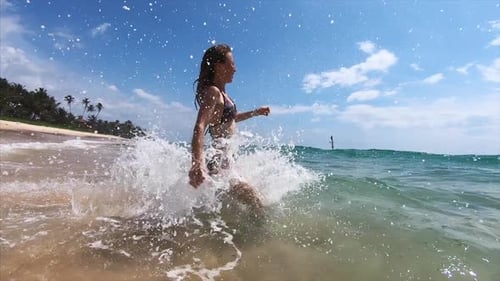 Young woman runs into the tropical sea with