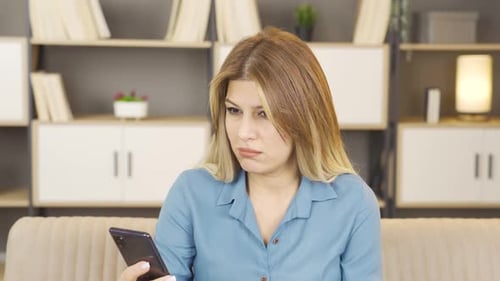 Woman looks at phone, frustration