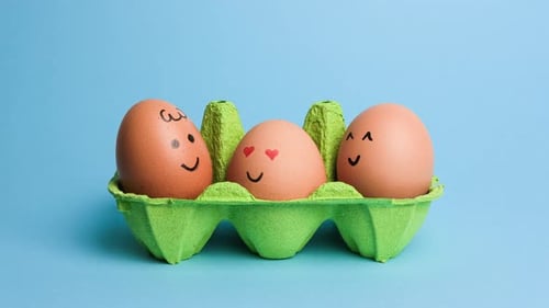 Cute Easter Eggs with Funny Faces in Green Box Isolated on Blue Background