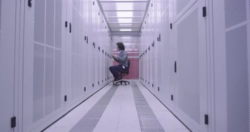 Ingénieur informatique ou spécialiste de la science des données travaillant sur une tablette dans une salle de serveurs dans un cloud moderne