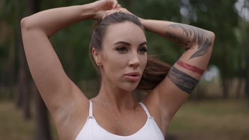 Woman Fixing Her Hair During Yoga Session in a Peaceful Forest Setting