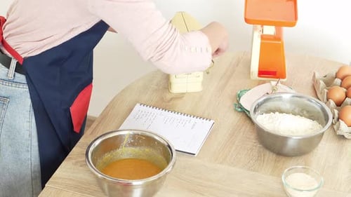Weibliche Hände mischen Eigelb in einer Schüssel mit Kuchenteig und Schneebesen in der Küche. Prozess zum Kochen von Cookies.
