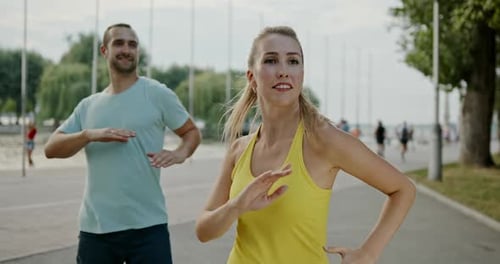 Man and Woman Exercising Arms Outdoors on Pathway