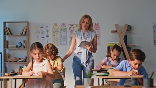 Group Children Doing Homework Sitting Class Desks Young Woman Teacher Watching