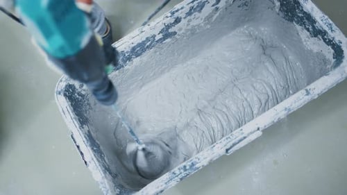 Mixing Construction Material in a Bucket A CloseUp View of a Worker Using a Drill to Blend Concrete