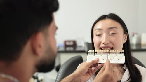 Dentist Examines Young Woman's Teeth with Shade Guide