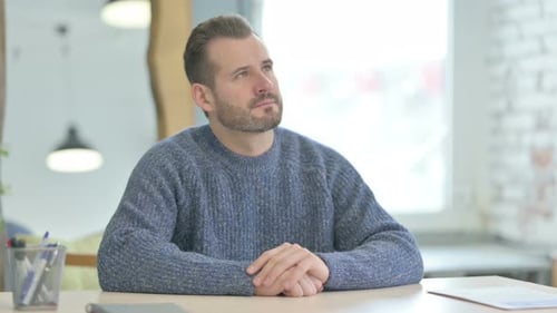 Pensive Middle Aged Man Thinking while Sitting at Work
