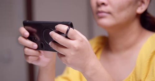 Clutching a digital mobile phone with both hands as the woman is playing and browsing some games and