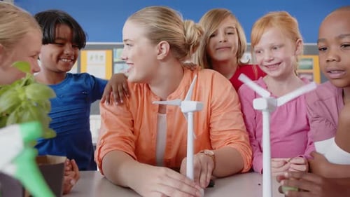 In school, female teacher and students learning about wind turbines in classroom