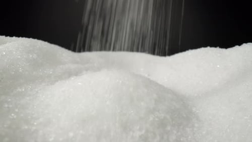 White sugar delicately cascading onto a sleek black background