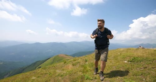 Aerial shot of a carefree man tourist with backpack is hiking on the path in the middle of hills s