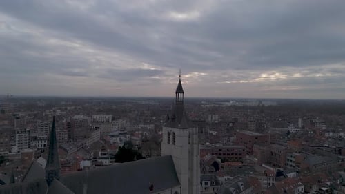 Drone shot of a church top in a city center on a cloudy day revealing the church.