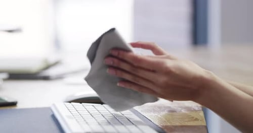 4k video footage of a businesswoman disinfecting her keyboard and workspace in a modern office