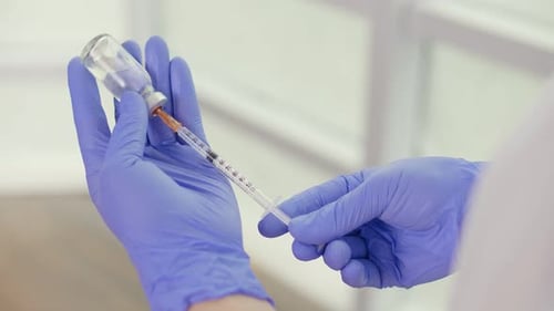 Hand Holding Syringe and Vaccine Ampoule with a Vaccine Health Care