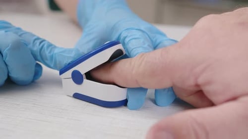 Doctor using pulse oximeter measures oxygen level in blood of man in medical office close-up, finger