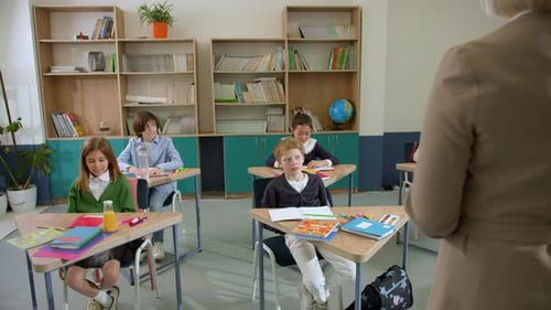 Elementary School Class Children Communicate with the Teacher Answering Question