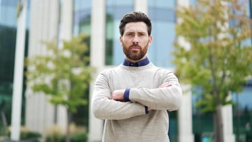 Portrait of a serious businessman standing confidently with arms crossed outside in an urban city