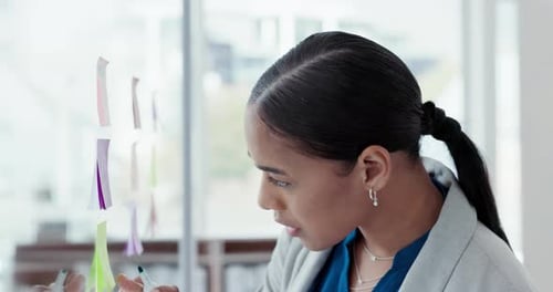 Brainstorming, business woman and writing a note with ideas and planning a strategy in office