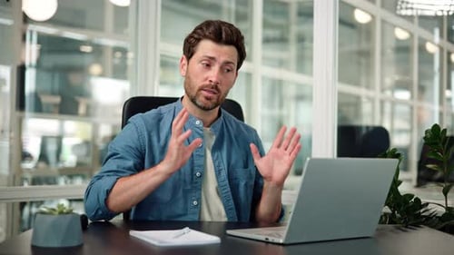 Man Video Conferencing on Laptop in Modern Office