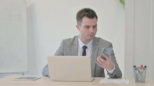 Young Adult Uses Smartphone in Office Environment