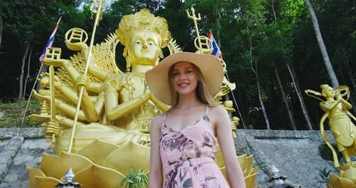 Young Woman Posing by Golden Buddha Statue