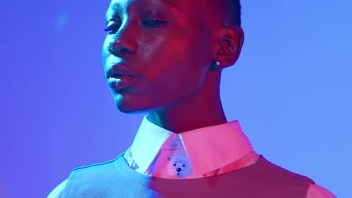 Dramatic extreme close-up of a young African American female model with red blue studio lights.