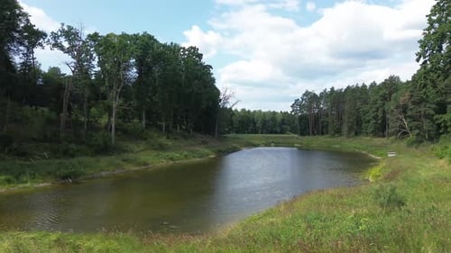 "Drone glides over Europe's dawn-lit lake, unveiling tranquil lagoon, lush forest, and natural ponds