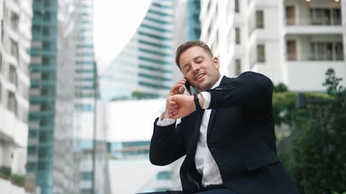 Businessman sitting at bench while talking to manager by using phone. Urbane.