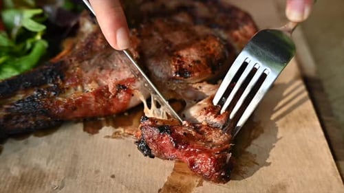 Woman eating beef stake at a restaurant with vegetables
