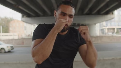 Young Muscular Athlete Close Up Working Out Powerful Punches with Passion While Boxing with a Shadow