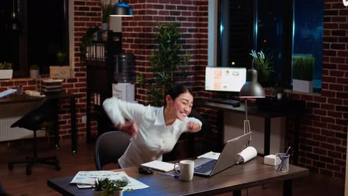Excited Woman Celebrates Success in Office at Night